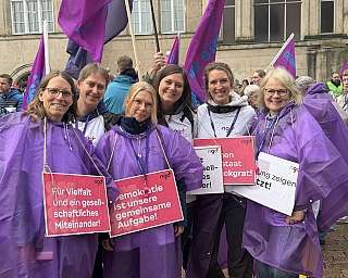 Gruppe von Frauen bei Demonstration mit lila Regenponchos und Schildern