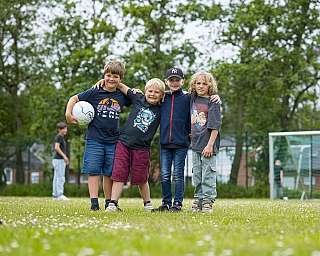 Kinder posieren auf dem Fussballplatz