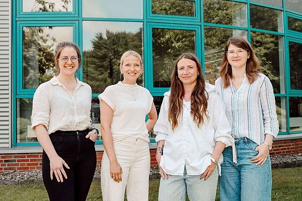 Vier Frauen lächelnd vor einem Gebäude