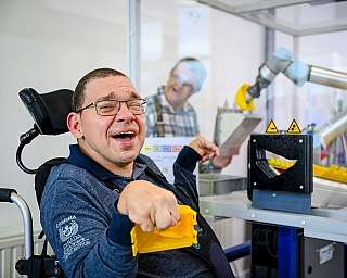Mann im Rollstuhl an einem Roboter